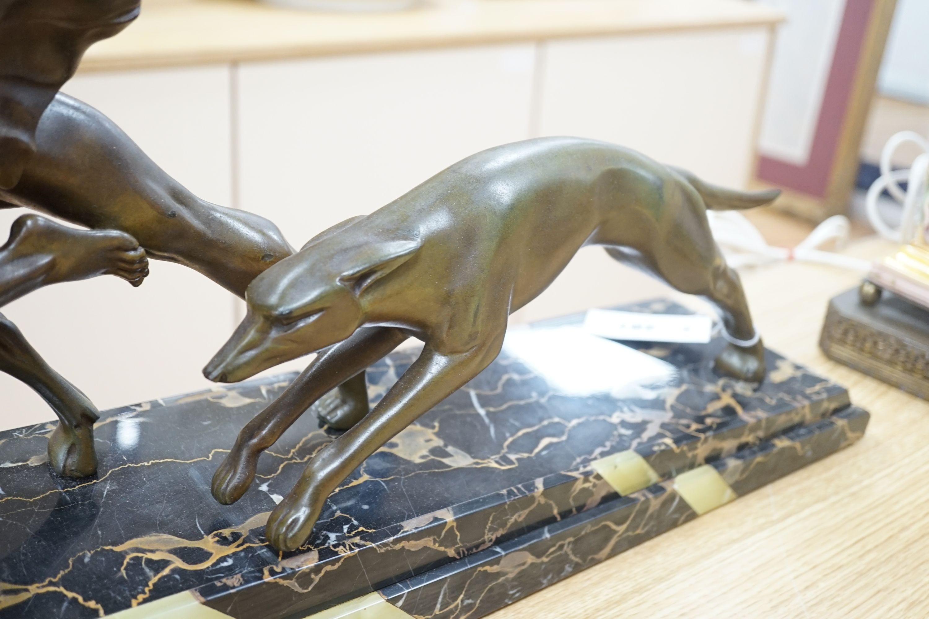 An Art Deco bronzed metal and marble running man with greyhounds, signed L Valderi, 85cm long